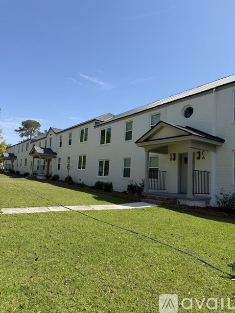 A white building with a green lawn in front.