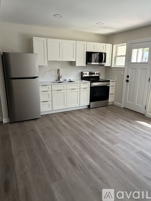 A kitchen with a refrigerator, microwave, oven, and cabinets.