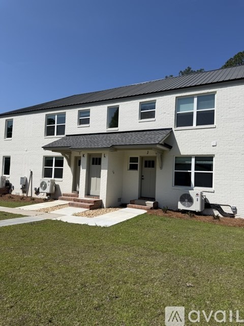 A white house with a black roof and a small porch.