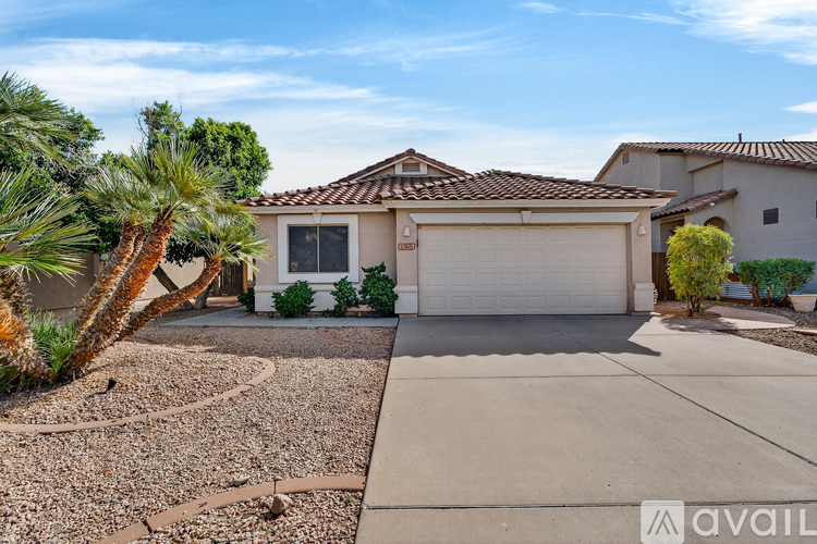 A house with a driveway and a palm tree in front.