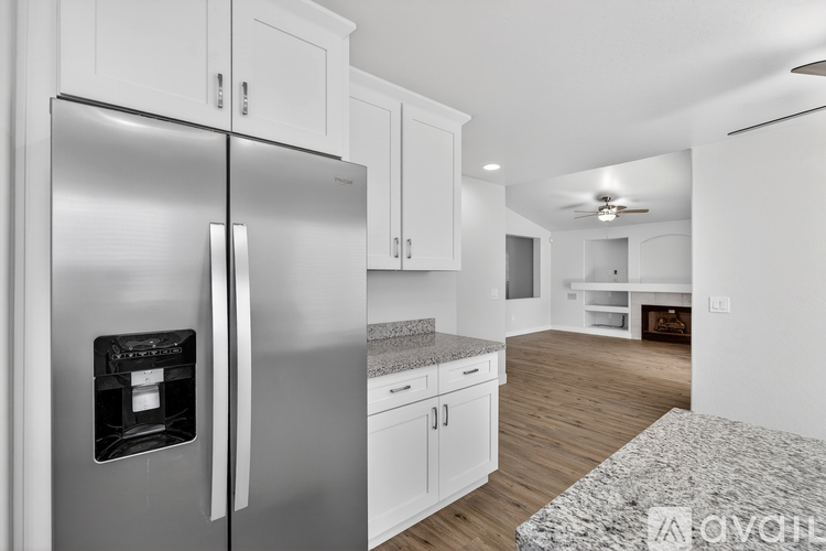 A modern kitchen with a stainless steel refrigerator and white cabinets.