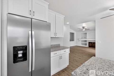 A modern kitchen with a stainless steel refrigerator and white cabinets.