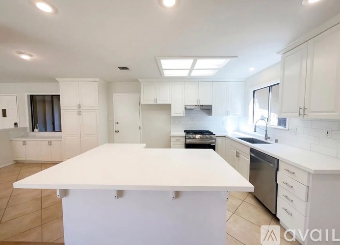 A kitchen with white cabinets and a large island in the center.