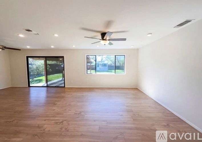 A spacious room with a ceiling fan and sliding glass doors.