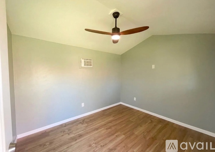 A room with a ceiling fan and wooden flooring.