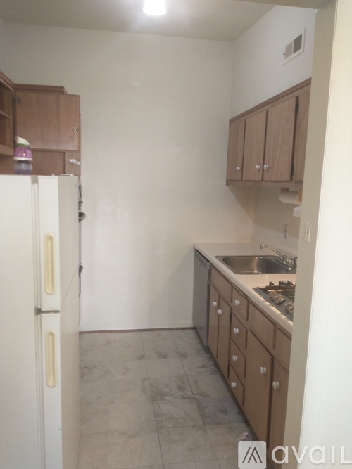A kitchen with a white refrigerator and brown cabinets.