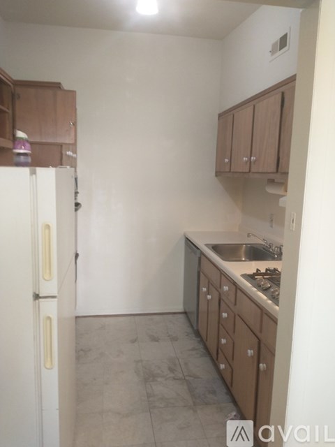 A kitchen with a white refrigerator and brown cabinets.