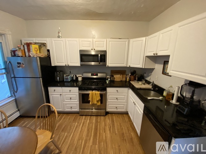 A kitchen with white cabinets and black countertops.