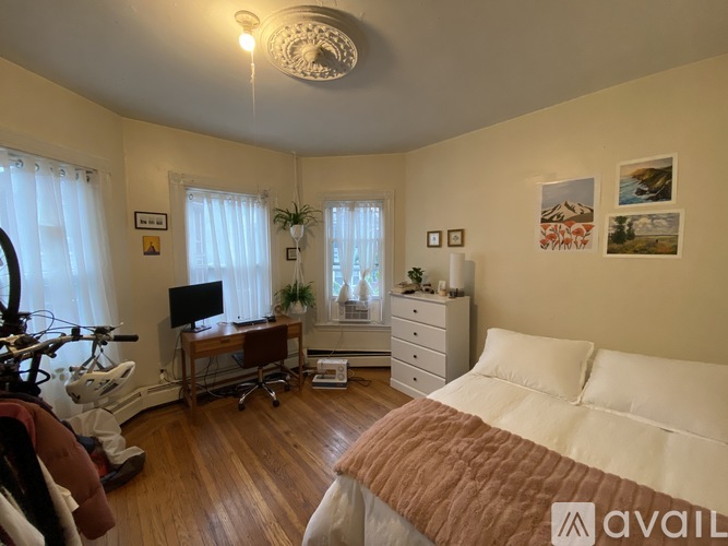 A bedroom with a bed, dresser, and a desk with a computer.
