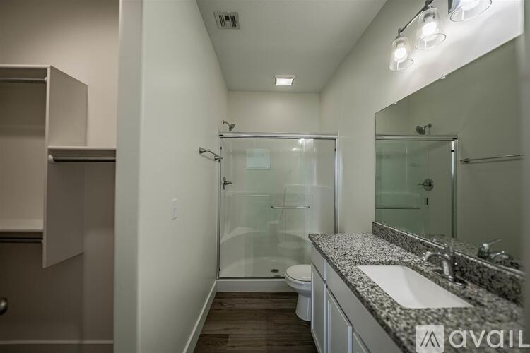 A bathroom with a walk-in shower, toilet, and double sinks.