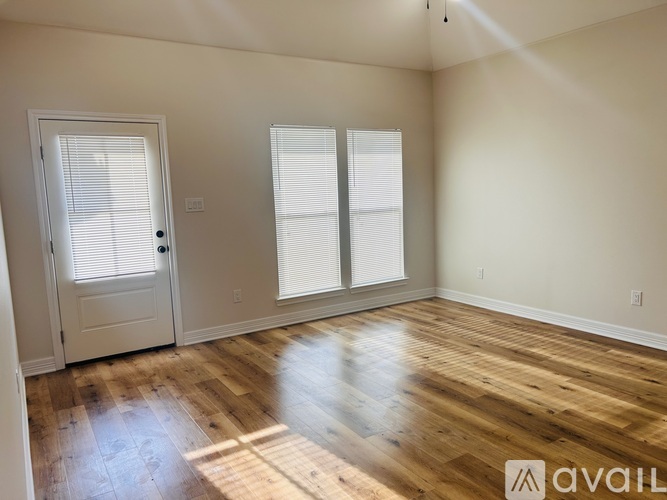 A room with wooden floors and a door with blinds.