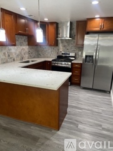 A kitchen with a marble countertop and wooden cabinets.