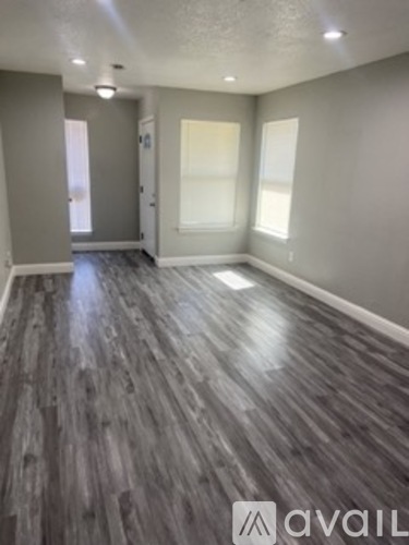 A room with wooden flooring and a doorway leading to another room.