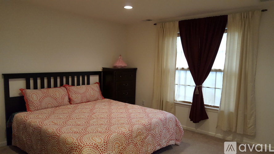 A bedroom with a bed covered in a red and white patterned bedspread.