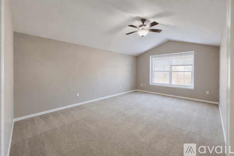 A spacious room with a ceiling fan and carpeted floor.