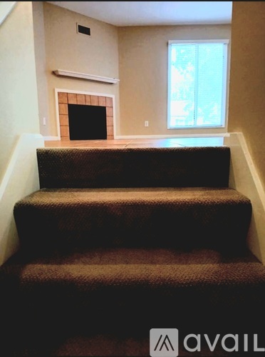 A staircase with a carpeted runner and a fireplace in the background.