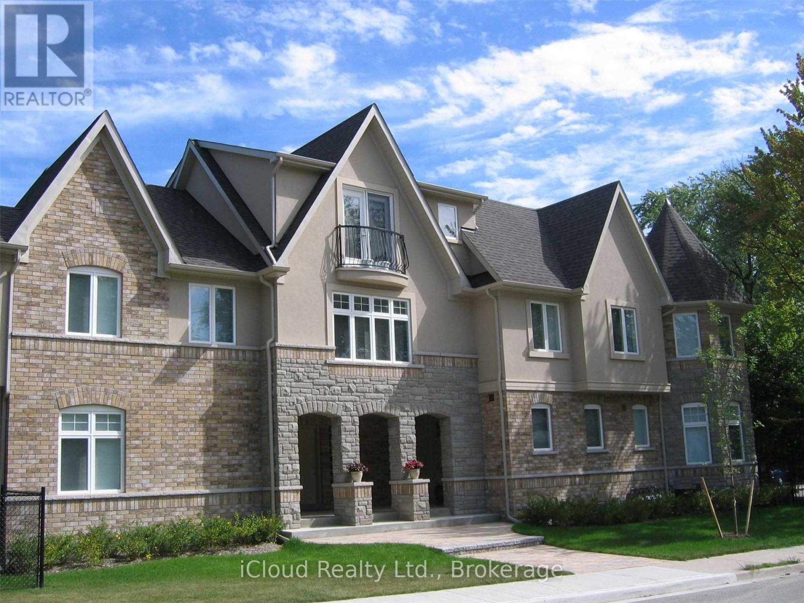 A large, multi-level house with a stone facade and a black fence in front.