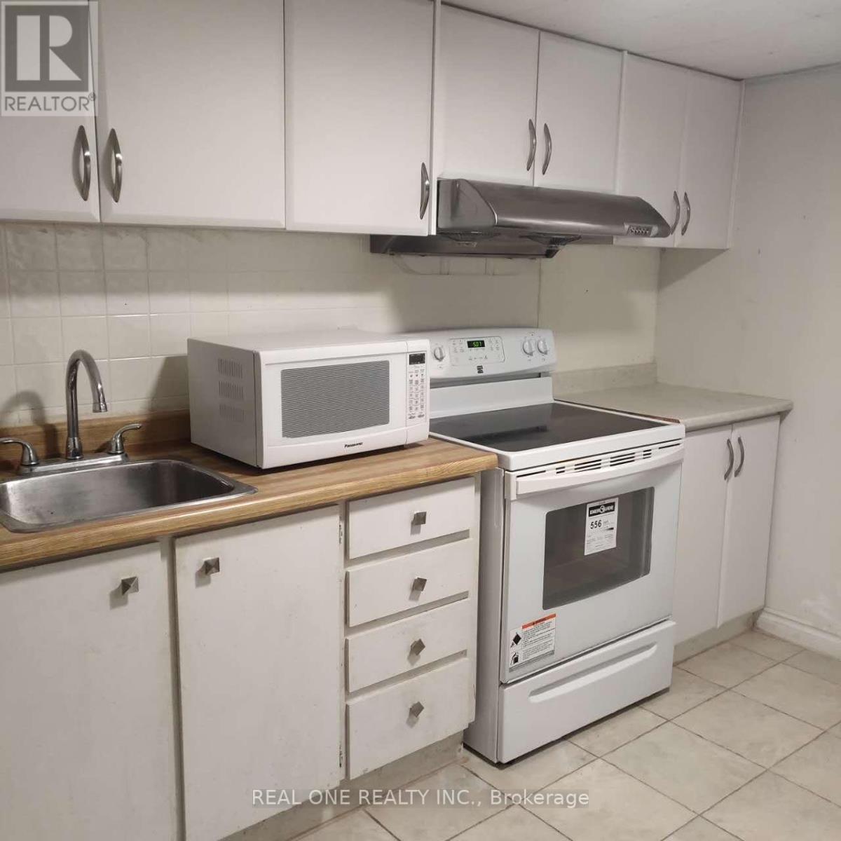 A white kitchen with a Realty Inc. logo.