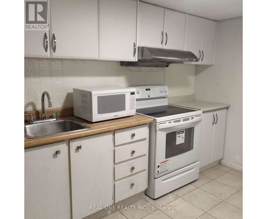A white kitchen with a Realty Inc. logo.