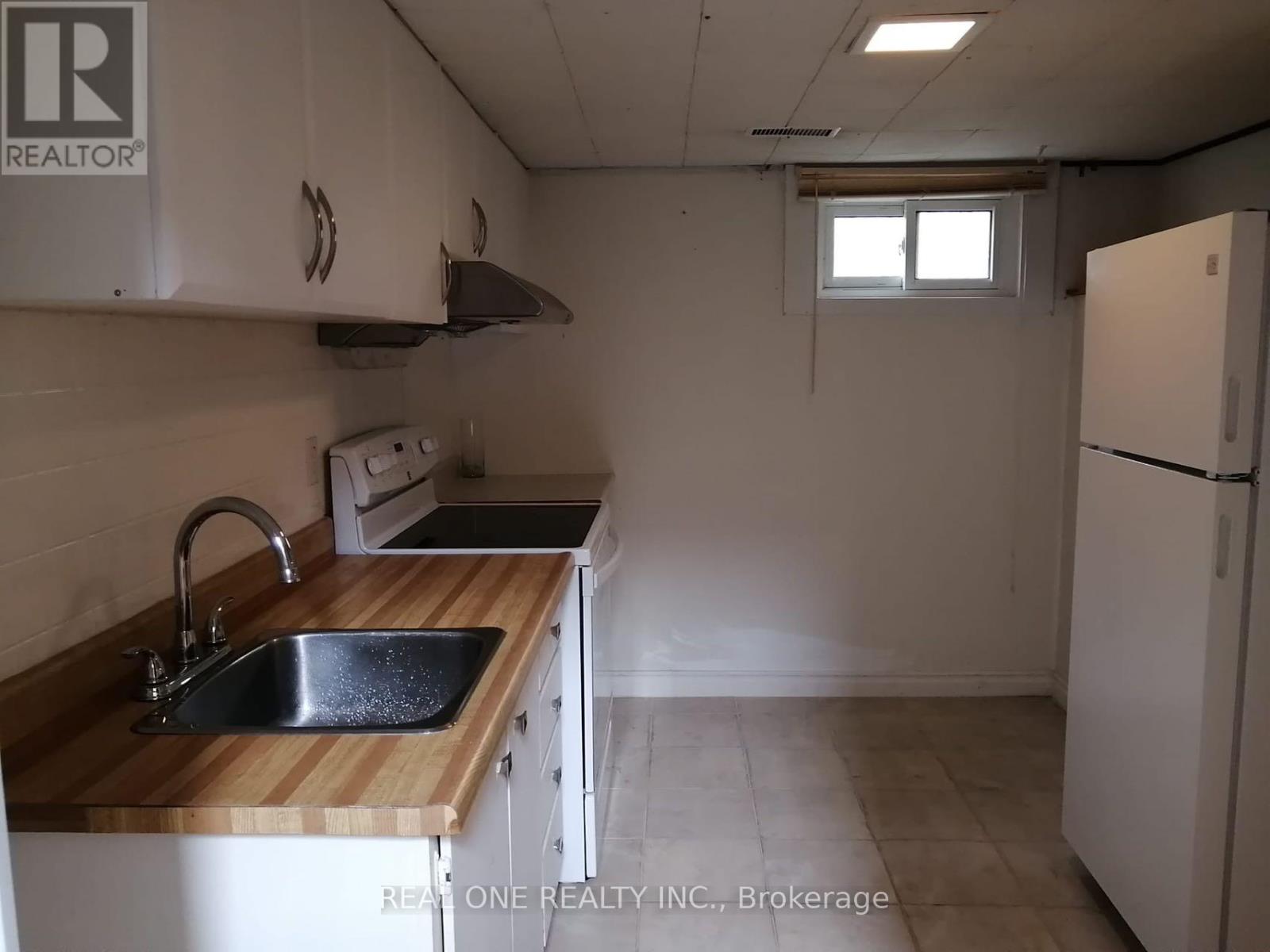 A kitchen with a sink, stove, and refrigerator.