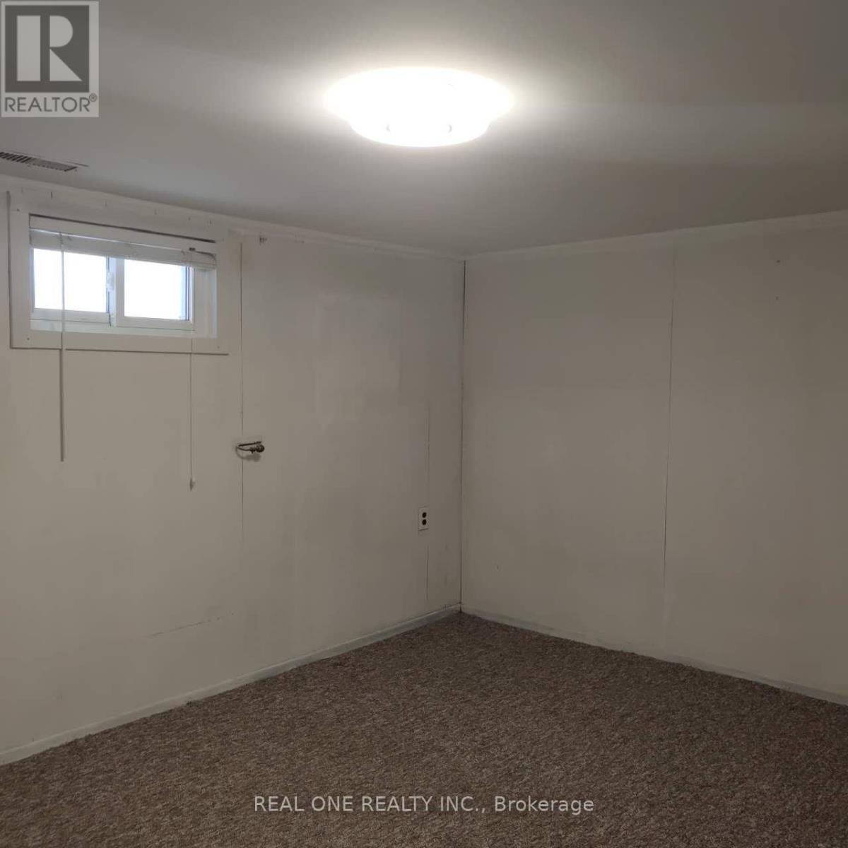 A room with a window and a carpeted floor.