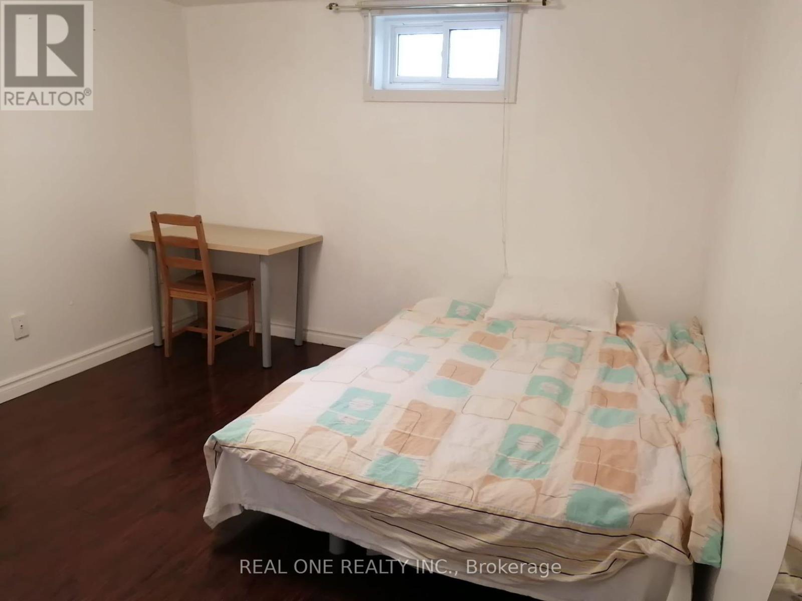 A bedroom with a bed, desk, and chair.