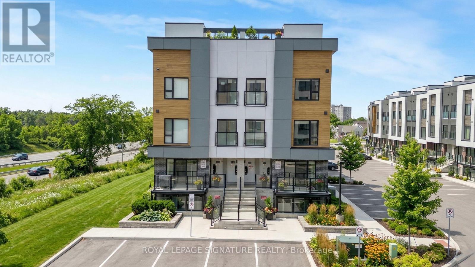 A modern multi-story building with a parking lot in front and a sign that reads "Royal LePage CNATURE REALTY BIO".