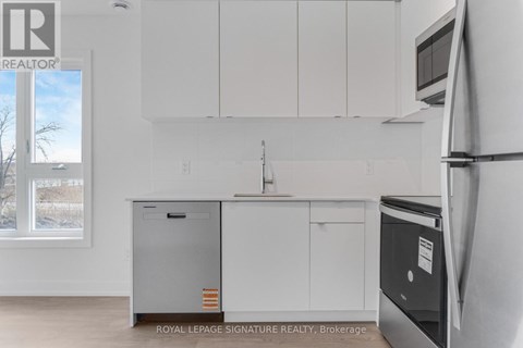 A kitchen with white cabinets and a black fridge.