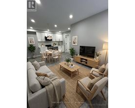 A modern living room with a grey couch, wooden chairs, and a television.