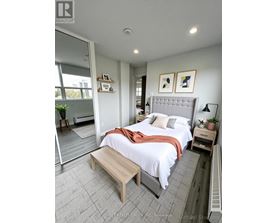 A bedroom with a bed, nightstand, and a window.