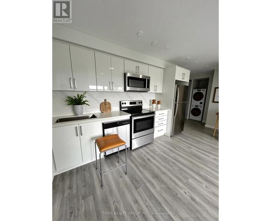 A modern kitchen with white cabinets and a wooden floor.