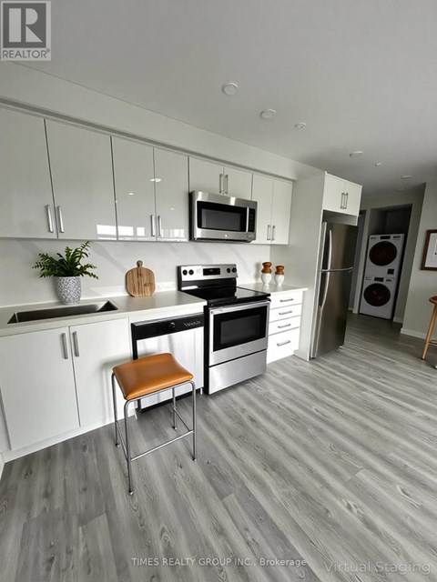 A modern kitchen with white cabinets and a wooden floor.