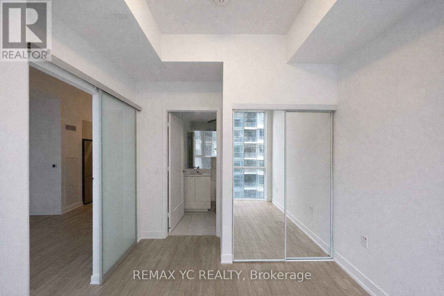A brokerage sign is on the wall of a large, empty room.