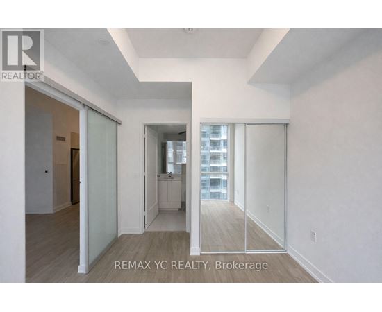 A brokerage sign is on the wall of a large, empty room.
