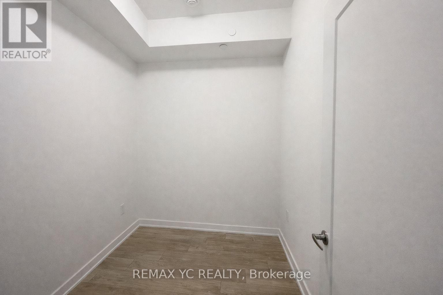 A small, empty room with a wooden floor and white walls.