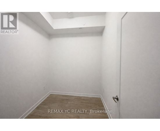 A small, empty room with a wooden floor and white walls.