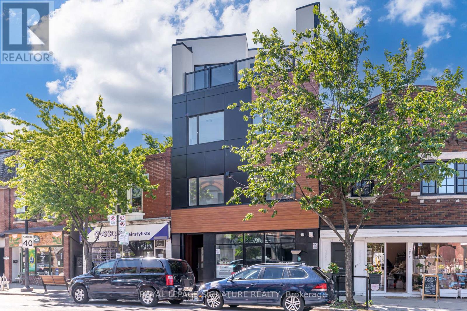 A black car is parked in front of a building with a sign that says "REALTOR".