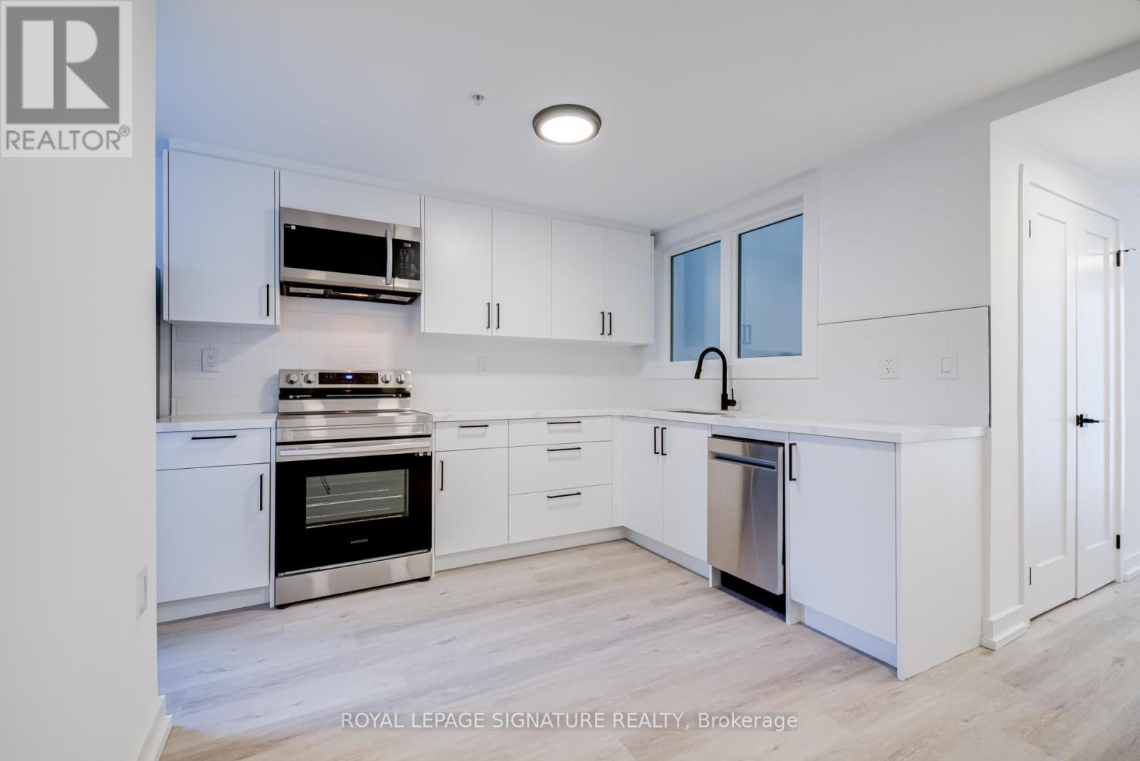 A modern kitchen with white cabinets and stainless steel appliances.