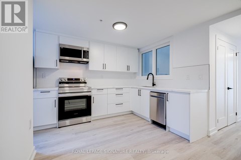 A modern kitchen with white cabinets and stainless steel appliances.