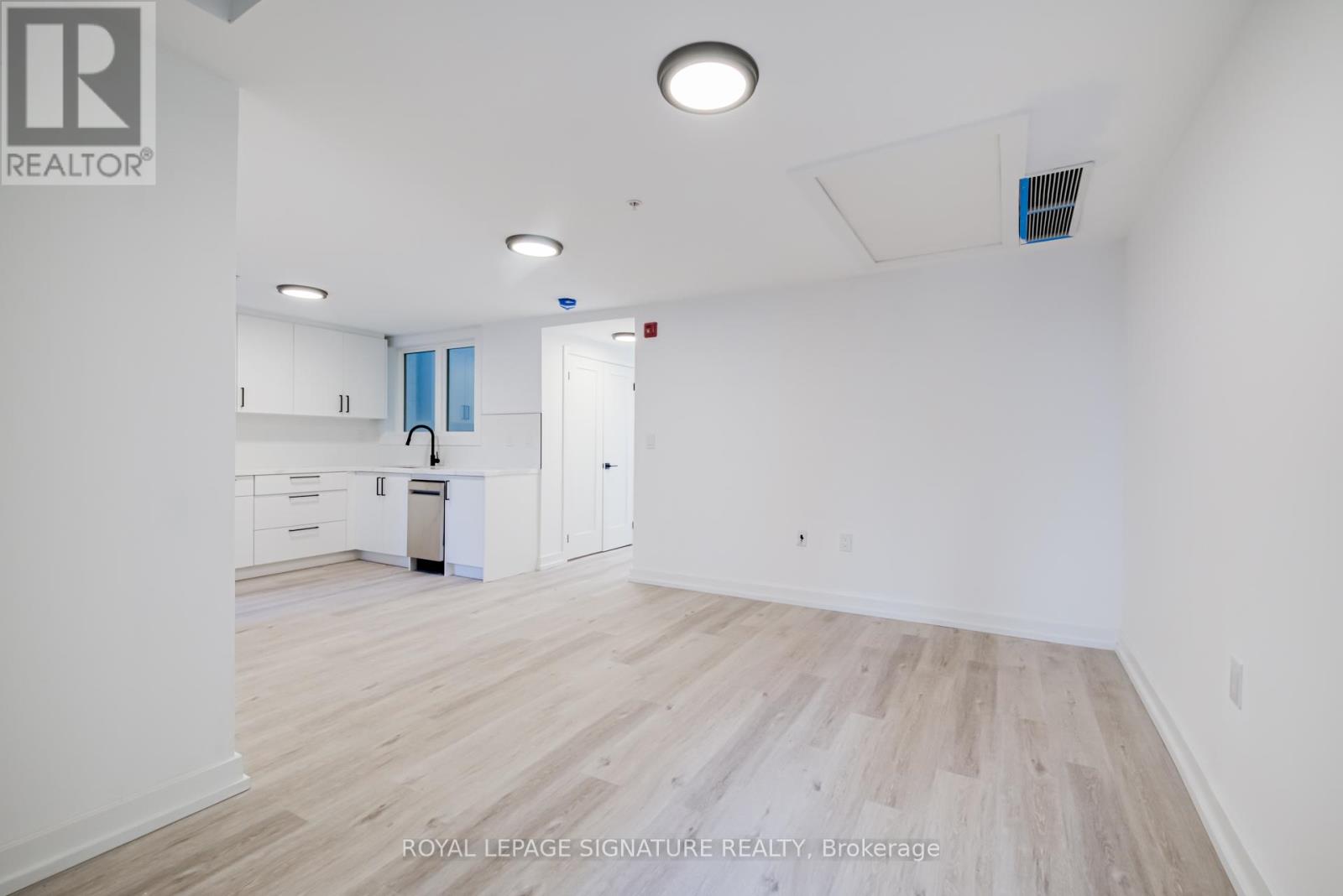 A white room with wooden flooring and a ceiling light.