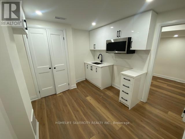 A small kitchen with white cabinets and a microwave above the stove.