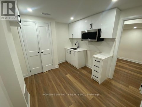 A small kitchen with white cabinets and a microwave above the stove.