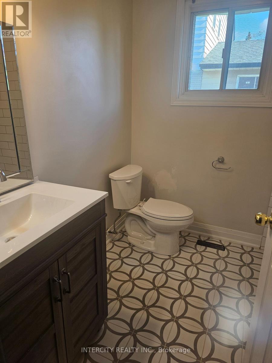 A bathroom with a toilet, sink, and tiled floor.