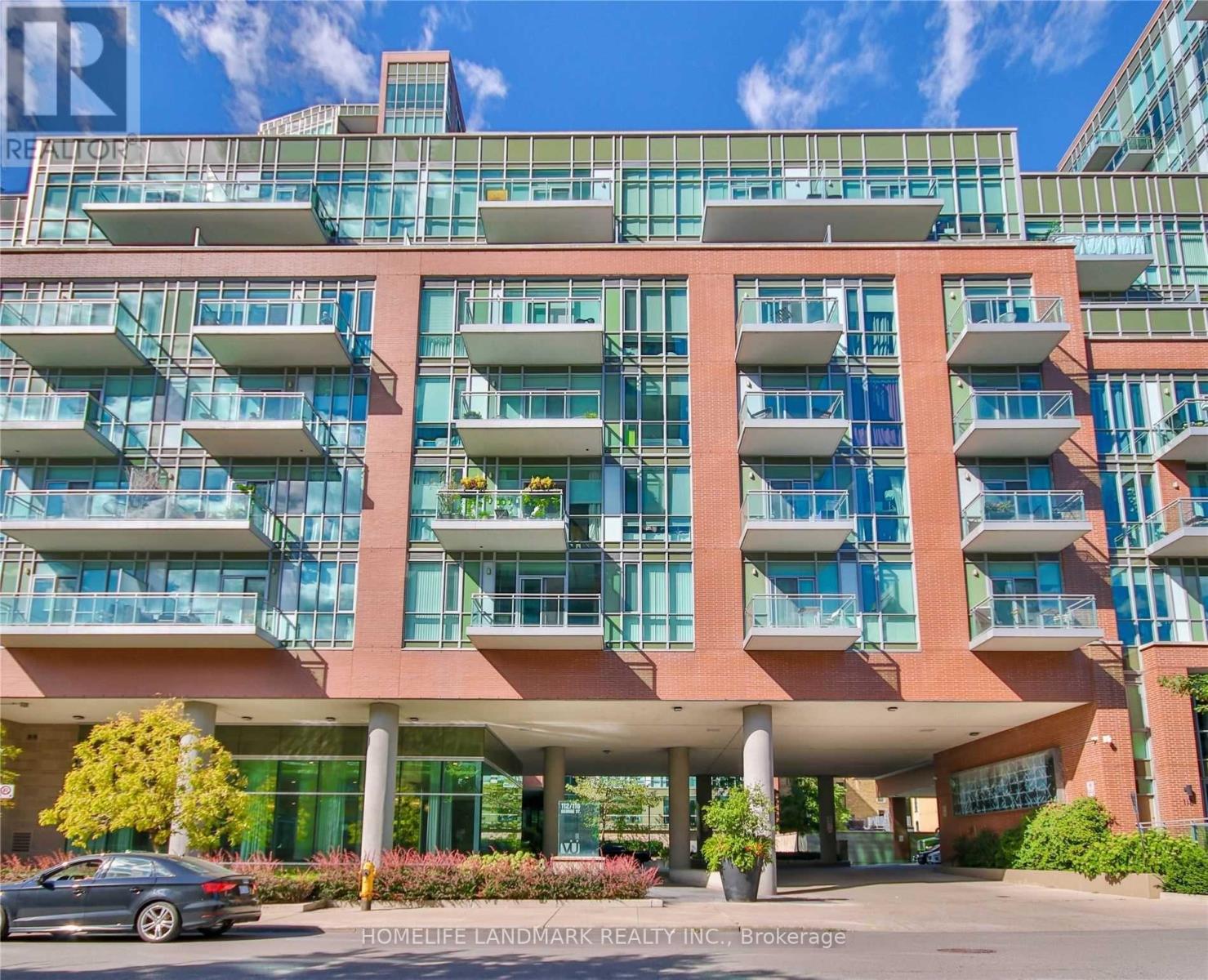 A modern multi-story building with balconies and a car parked in front.
