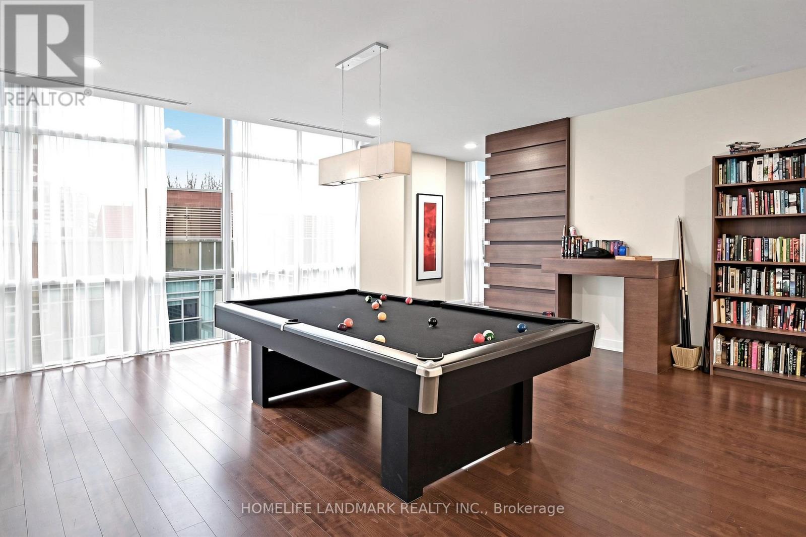 A pool table in a room with a bookshelf and a window.