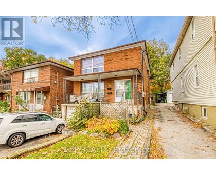 A white car is parked in front of a brick house.