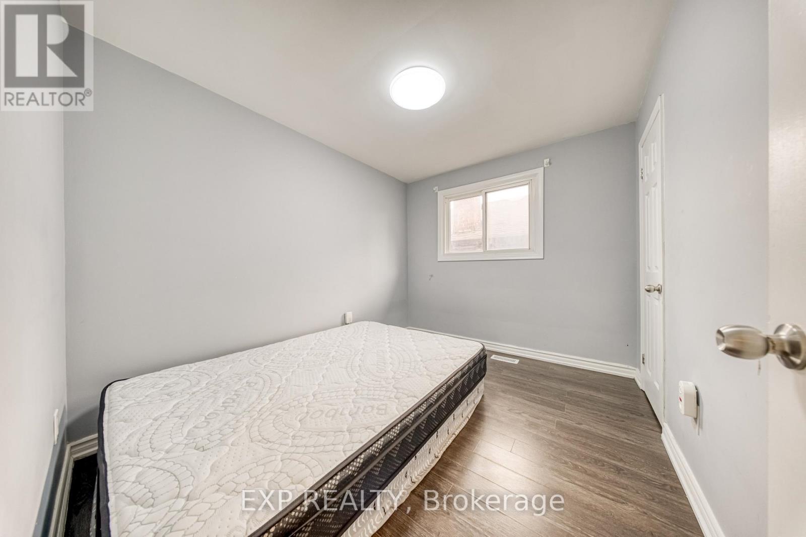 A bedroom with a bed, wooden floor, and a window.