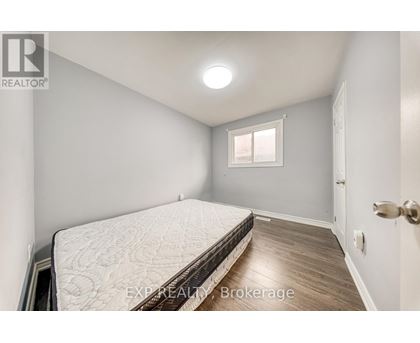 A bedroom with a bed, wooden floor, and a window.