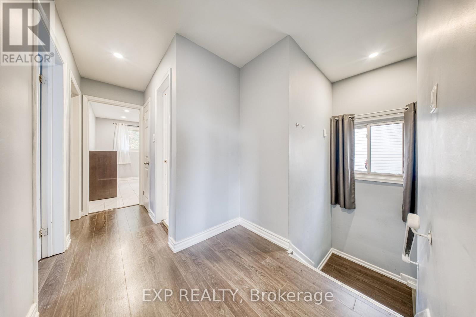 A well-lit, empty room with a window and a door leading to another room.