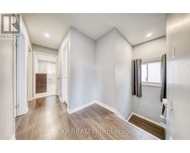 A well-lit, empty room with a window and a door leading to another room.